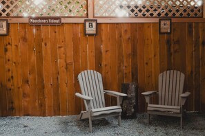 Dos sillas Adirondack frente a una valla de madera con letreros que dicen "Moonshiners Hideout" y "Se busca!"