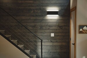 Eine Treppe mit Holzbodenstufen und Metallgeländer, die zu einer Zwischenebene mit einer Leuchte führt.