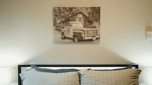 Un dormitorio con cama, dos almohadas y un cuadro colgado en la pared de una camioneta pickup.