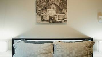 A bedroom with a bed, two pillows, and a wall-mounted picture of a pickup truck.