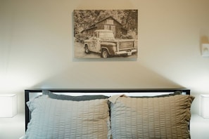 Ein Schlafzimmer mit einem Bett, zwei Kissen und einem Wandbild eines Pickup-Trucks.