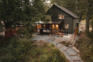 Eine Hütte mit einer Terrasse, umgeben von dichtem Wald.