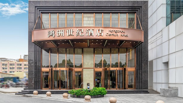 The exterior of the Hongzhugu Century Hotel with a modern facade, large glass windows, and a prominent entrance with a water feature in front.