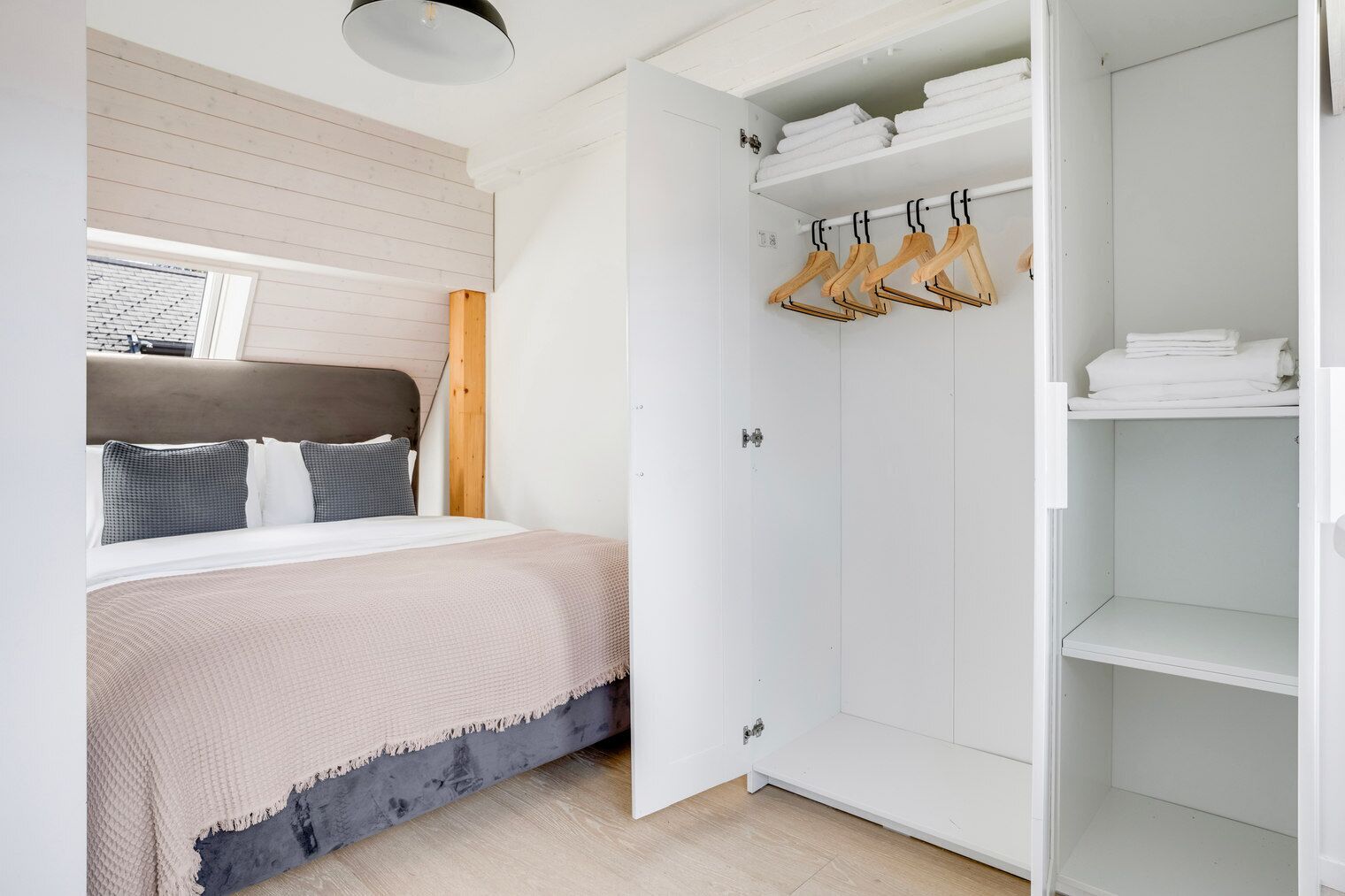A bedroom with a bed, a wardrobe, and a window.