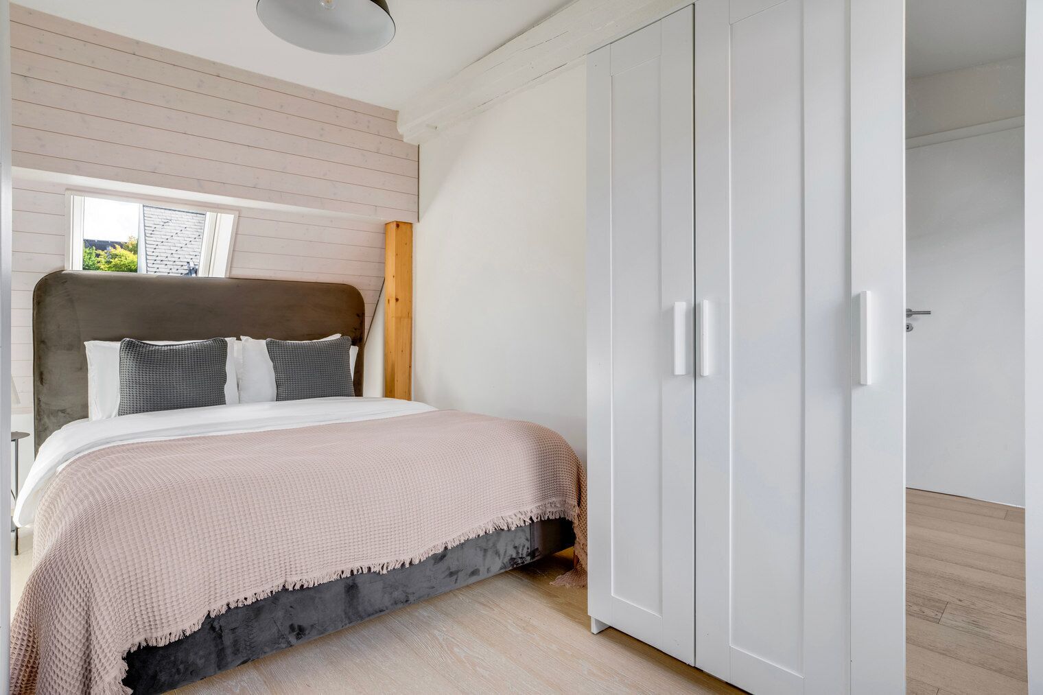 A bedroom with a bed, a wardrobe, and a window.