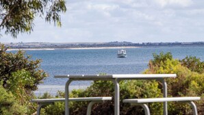 A bench overlooking a body of water with a boat in the distance. - Tumby Bay Caravan Park (Tumby Bay)