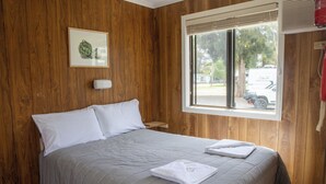 A bedroom with a bed, a window, and a framed picture on the wall. - Tumby Bay Caravan Park (Tumby Bay)