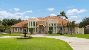 A large, two-story house with a stone facade, a tiled roof, and a central entrance with a decorative arch. - Valley Gateaway! Pool House (Mission)