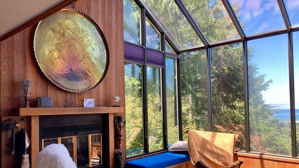 A modern living room with a fireplace, a large window with a view of the outdoors, and a cozy seating area.