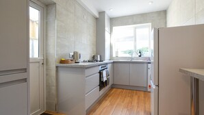Une cuisine moderne avec des meubles gris, un four encastré et une fenêtre qui laisse entrer la lumière naturelle.