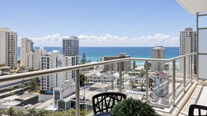 Un balcon avec vue sur l’océan et le paysage urbain.