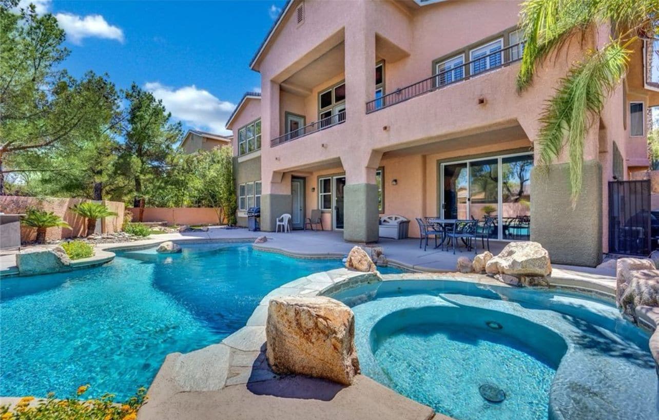 A hotel with a swimming pool, outdoor seating, and a two-story building.