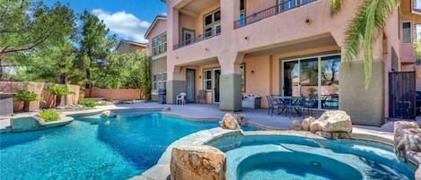 A hotel with a swimming pool, outdoor seating, and a two-story building.