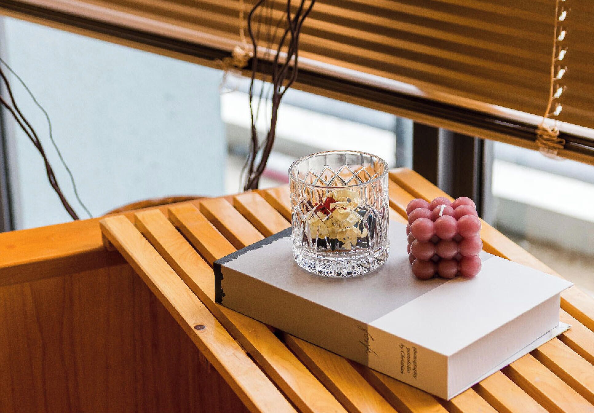 A wooden table with a book and a glass of wine.