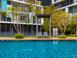 A modern building with a pool, two lounge chairs, and a pergola structure.