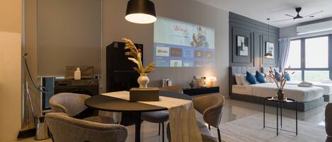 A modern living room with a dining area, a large screen displaying a movie, and a ceiling fan.