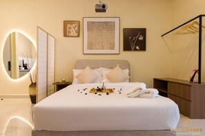 Une chambre d’hôtel avec un lit bien fait, une table de chevet, un miroir et des œuvres d’art accrochées au mur.