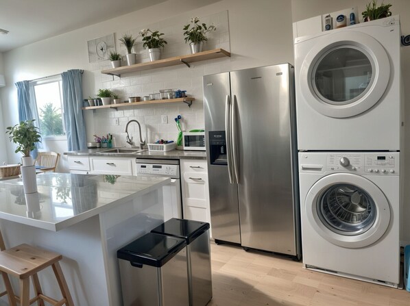 Una cocina moderna con una isla central, electrodomésticos de acero inoxidable y lavadora integrada.