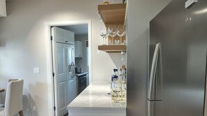 A modern kitchen with a stainless steel refrigerator, a marble countertop, and a wine rack.