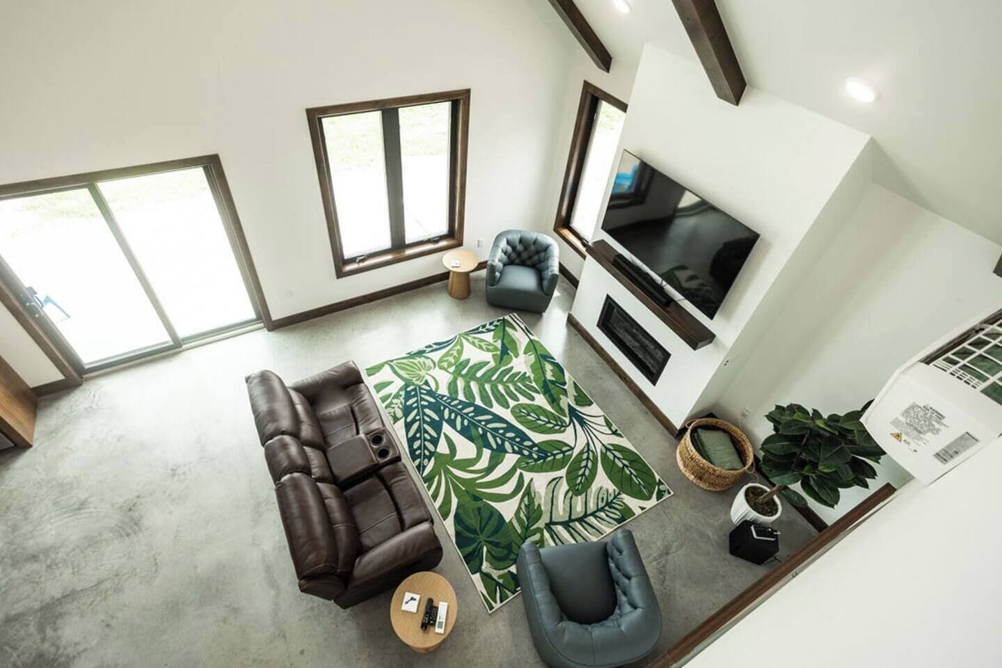 Un salon moderne avec un canapé d’angle, une table basse, un téléviseur et une grande fenêtre.
