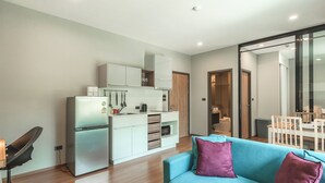 A modern apartment with a kitchenette, a blue sofa, and a dining area. - 1BR Pool Access Near Rawai Beach C222 (Rawai)
