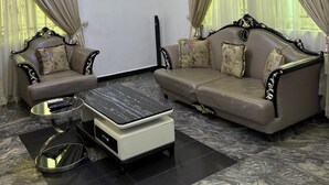 Ein Wohnzimmer mit einer Sofagarnitur, einem Couchtisch und einer Deckenleuchte.