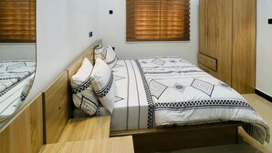 Ein Schlafzimmer mit einem Bett, einem Holzschrank, einem Spiegel und einer Deckenleuchte.