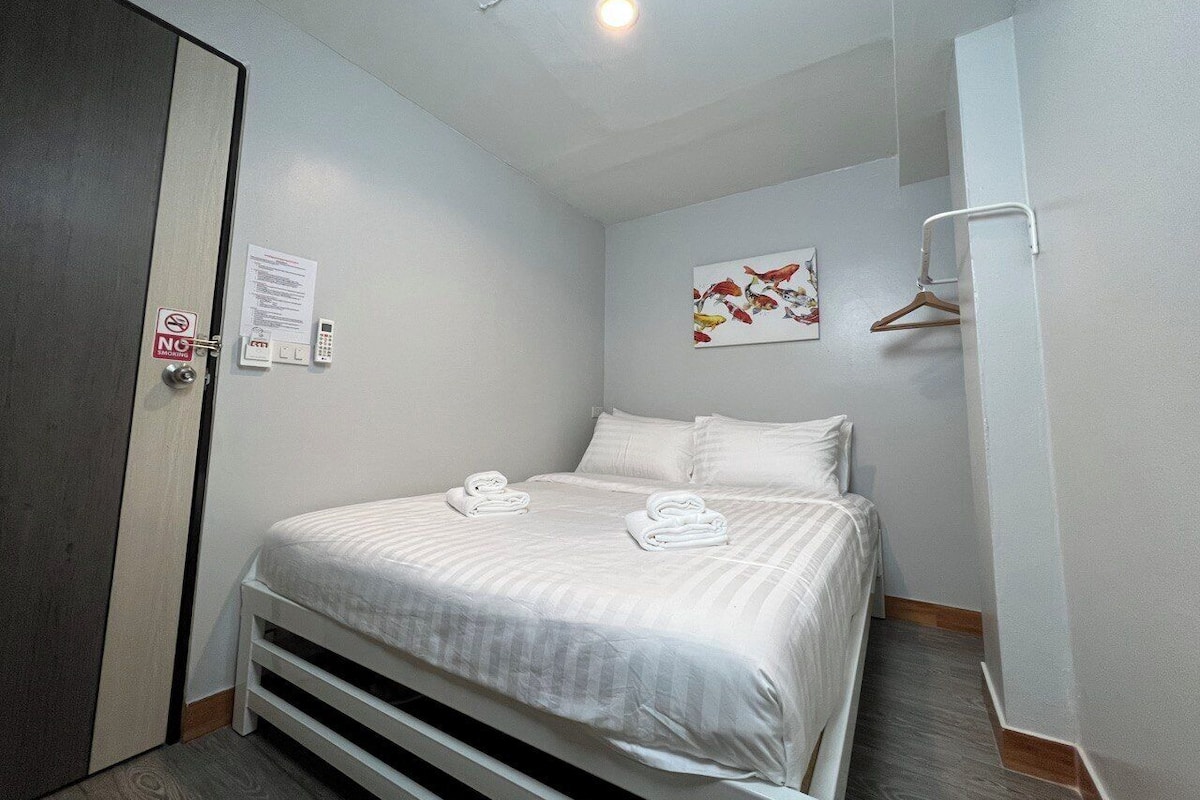 Een hotelkamer met een bed, een kledingkast, een deur met een 'Niet roken'-bordje, een wandtelefoon en een schilderij.