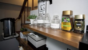 Une étagère contenant divers articles liés au café, notamment une machine à café, une tasse à café, ainsi que différents types de grains de café et de capsules.