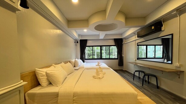 Une chambre d’hôtel avec un grand lit, un bureau avec une chaise et une fenêtre donnant sur un paysage verdoyant.