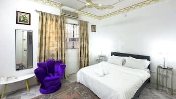 A bedroom with a bed, a chair, a mirror, and a window with curtains.