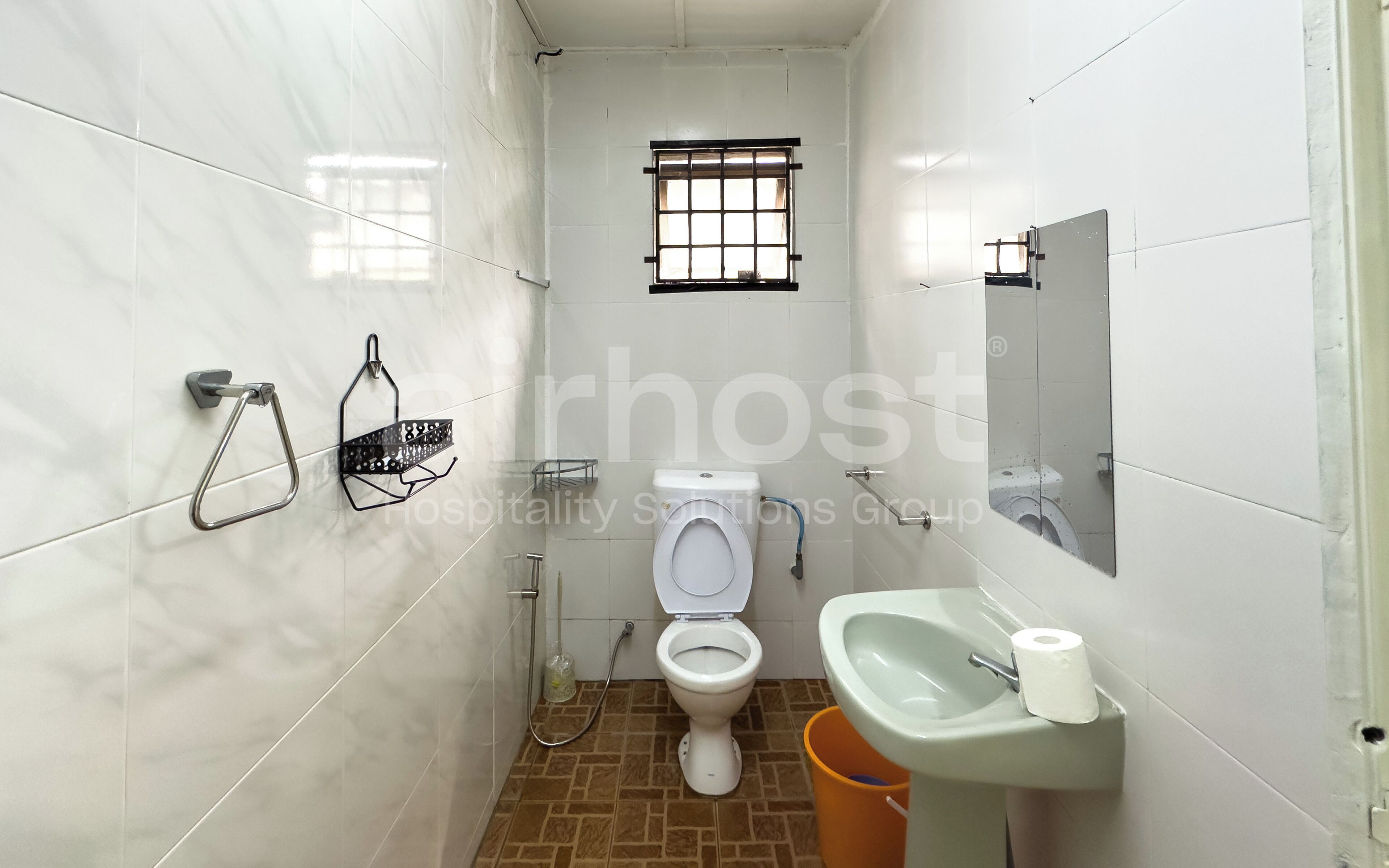 A small, tiled bathroom with a toilet, sink, and a window.