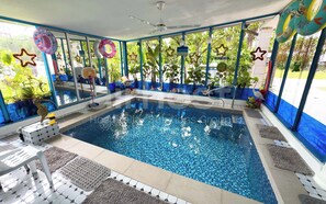 An indoor swimming pool with a clear view of the surrounding area, including a basketball hoop, star decorations, and a sign that reads "SWIM AT OWN RISK". - Family Home Ampang Utama (Ampang)