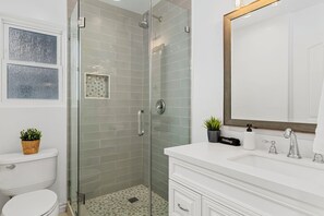 Une salle de bain avec une douche à parois de verre, un meuble-lavabo blanc et un grand miroir.