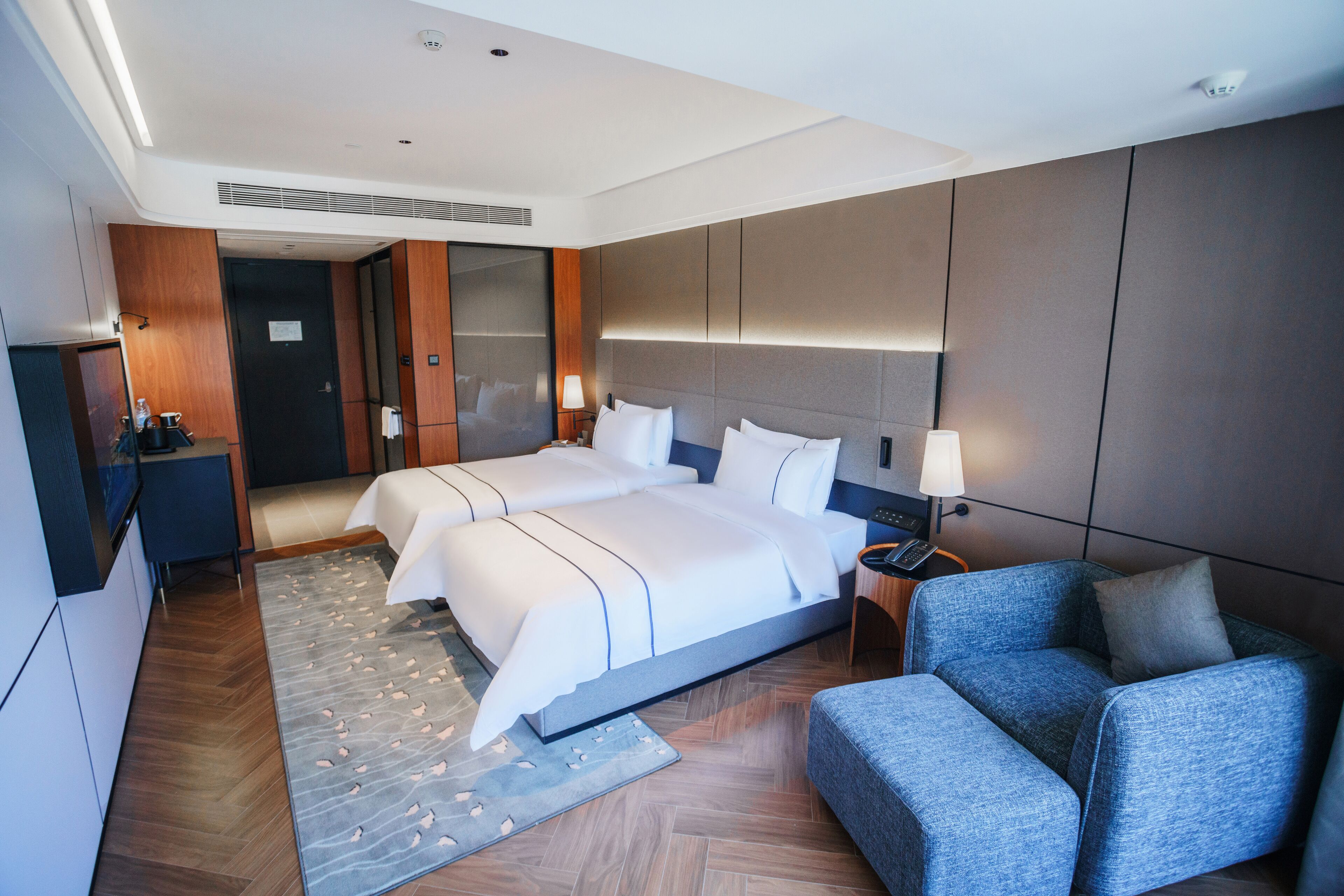 A modern hotel room with a large bed, a seating area, and a desk.