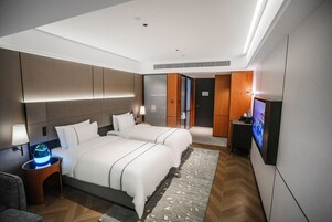 Ein modernes Hotelzimmer mit einem großen Bett, Nachttischen, einem Flachbildfernseher und einem dekorativen Teppich.
