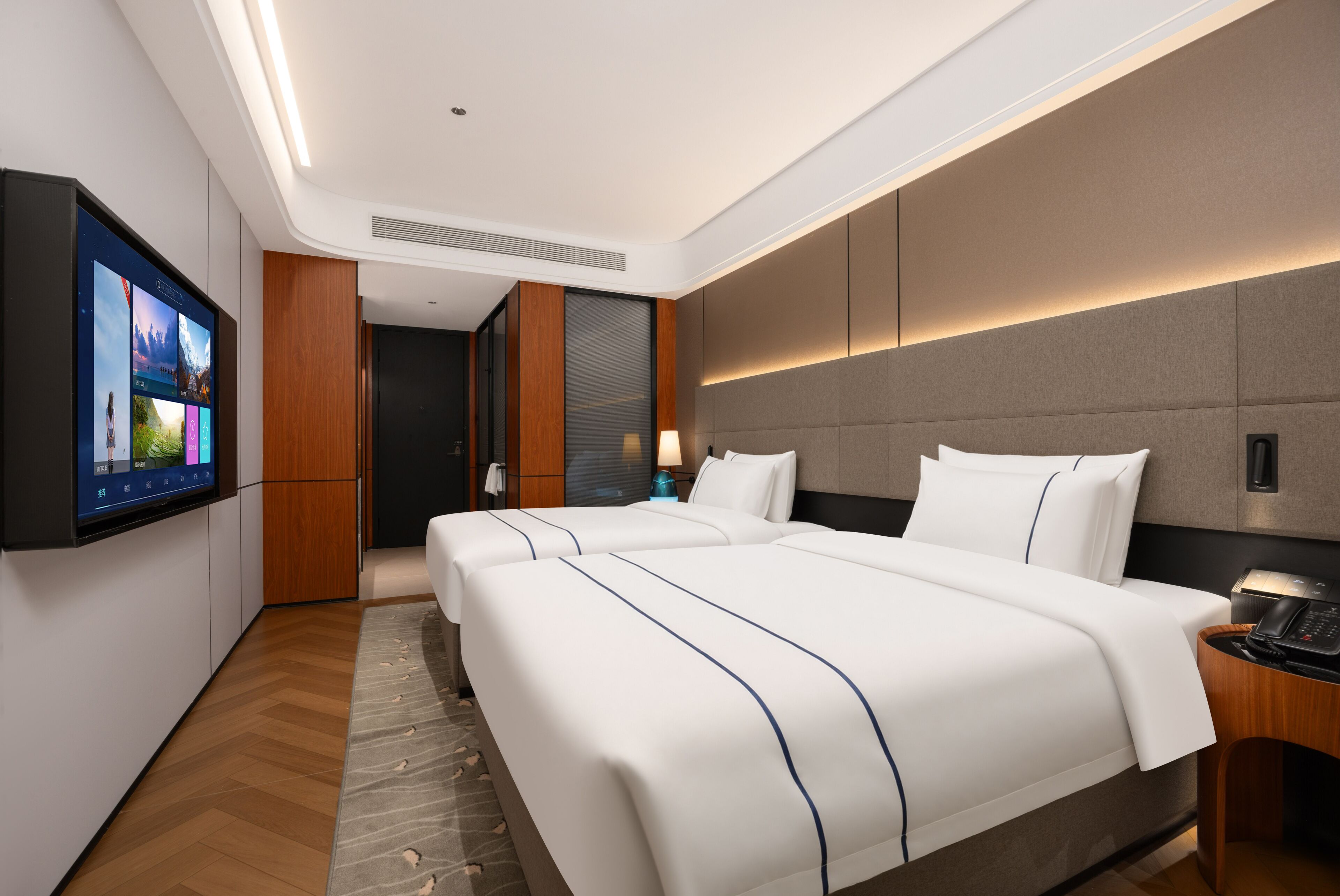 A hotel room with two beds, a flat-screen TV, a wooden floor, and a modern design.