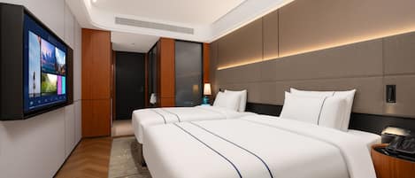 A hotel room with two beds, a flat-screen TV, a wooden floor, and a modern design.