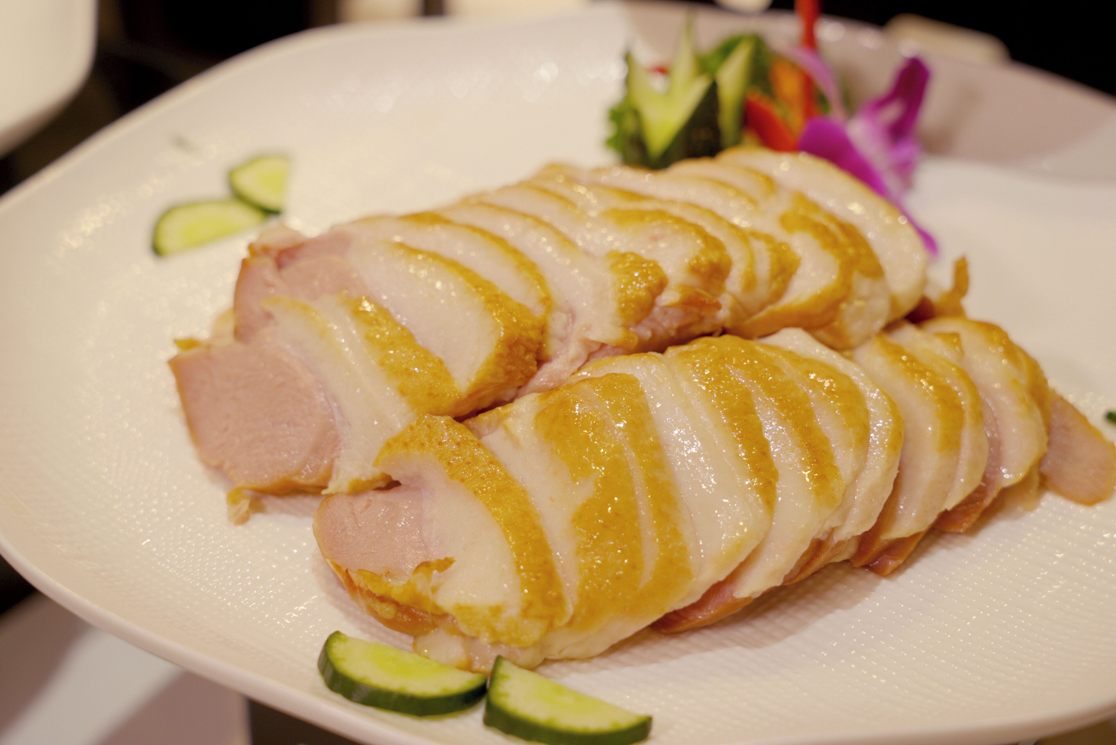 A plate with sliced meat and cucumber slices.