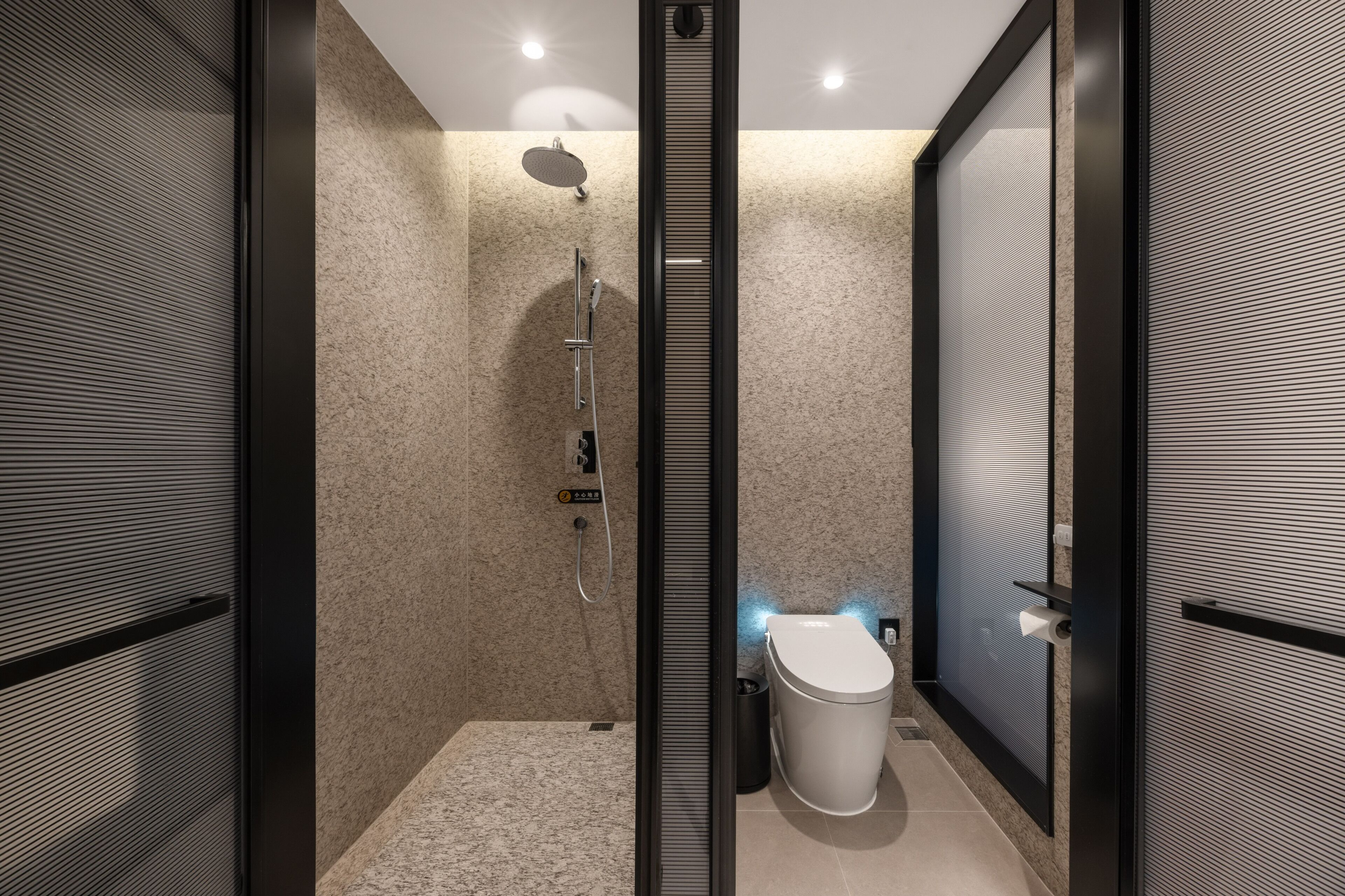 Un baño moderno con ducha, inodoro y mampara de vidrio.