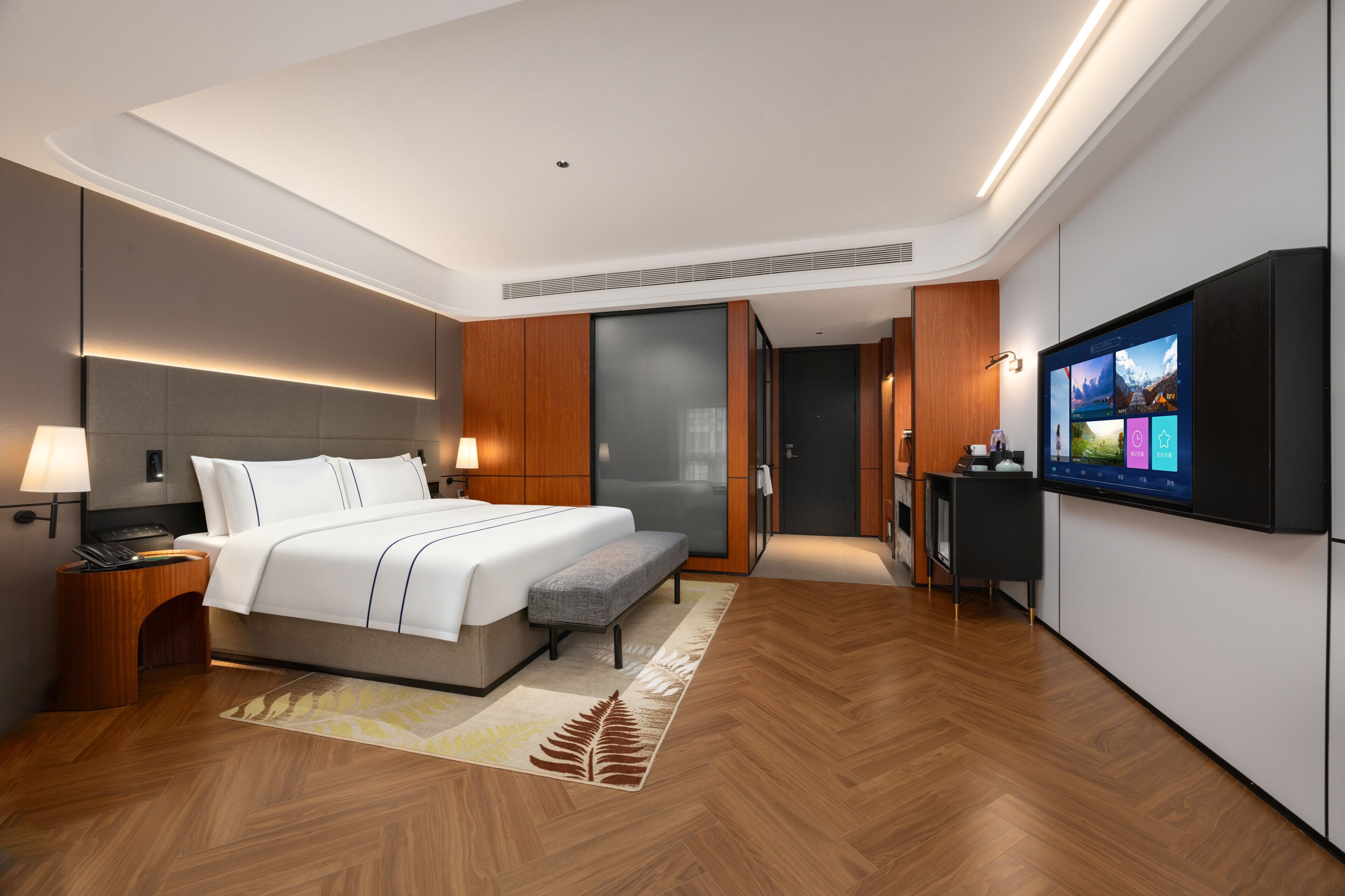 A modern hotel room with a bed, bedside table, TV, and a sliding door leading to a bathroom.