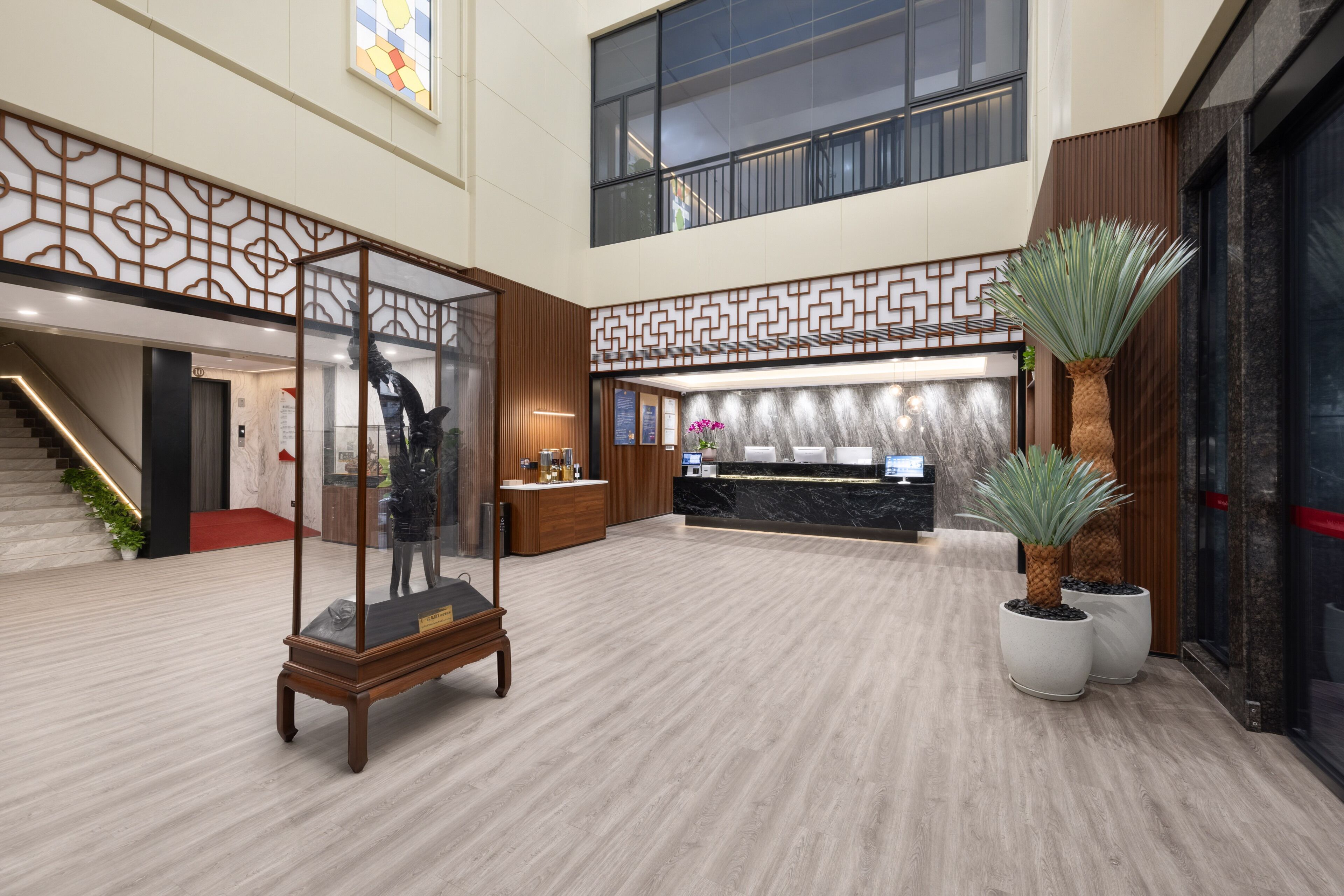 A spacious lobby with a reception desk, a staircase, and a large window.