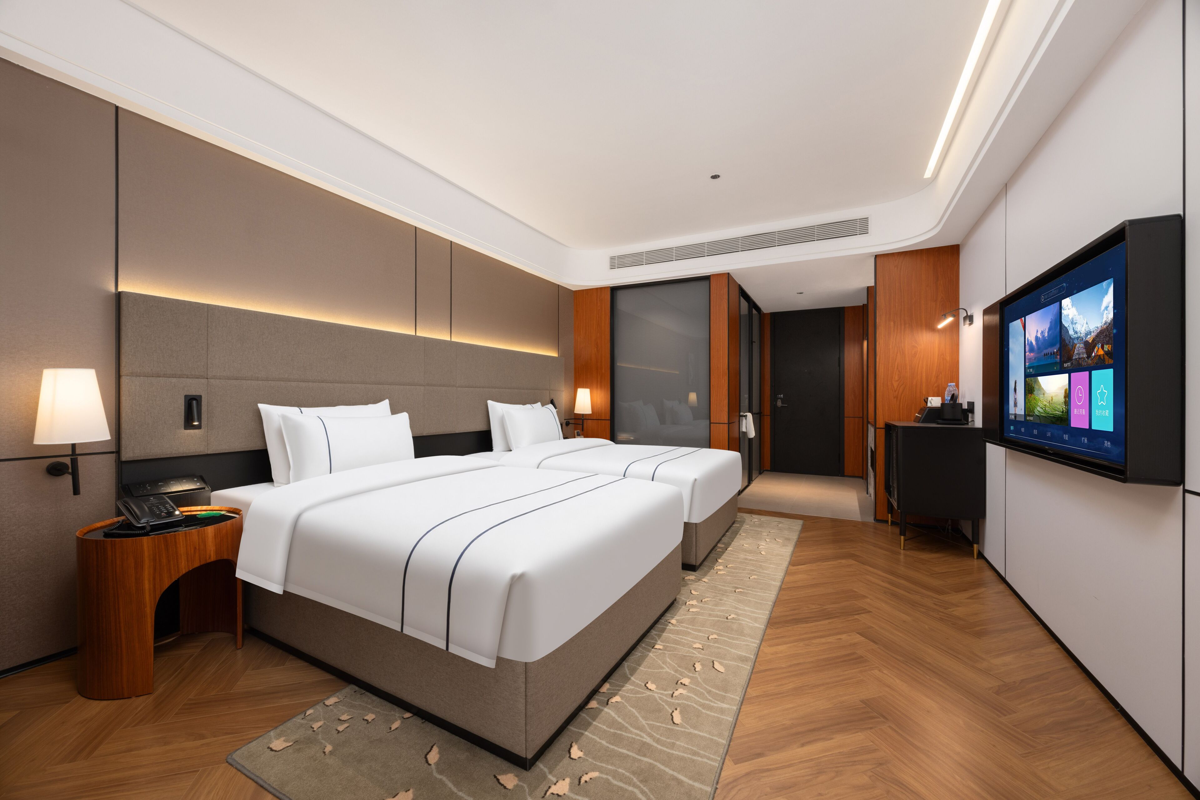 Habitación de hotel moderna con una cama grande, mesitas de noche, un televisor de pantalla plana y piso de madera.