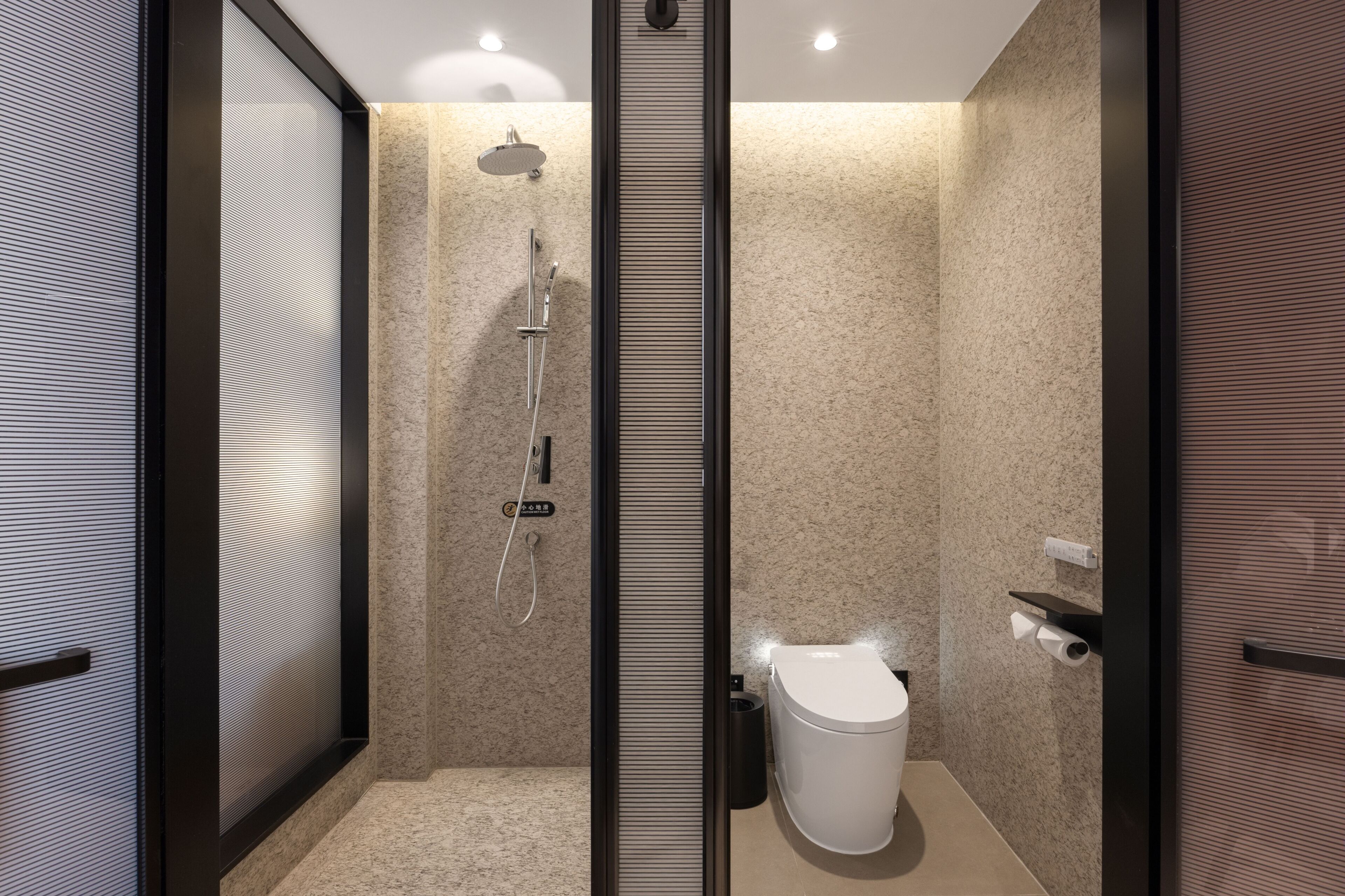Un baño moderno con ducha, inodoro y mampara de vidrio.