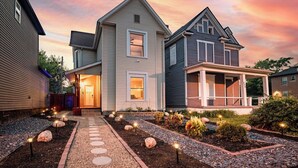 A two-story house with a front porch and a landscaped garden with stepping stones. - Backyard Escape: Outdoor Movie, Dome, Mini Golf, hot tub, fire pit, grill, mural (Columbus)