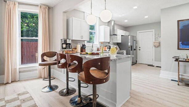 A modern kitchen with a central island, bar stools, and pendant lighting. - Backyard Escape: Outdoor Movie, Dome, Mini Golf, hot tub, fire pit, grill, mural (Columbus)