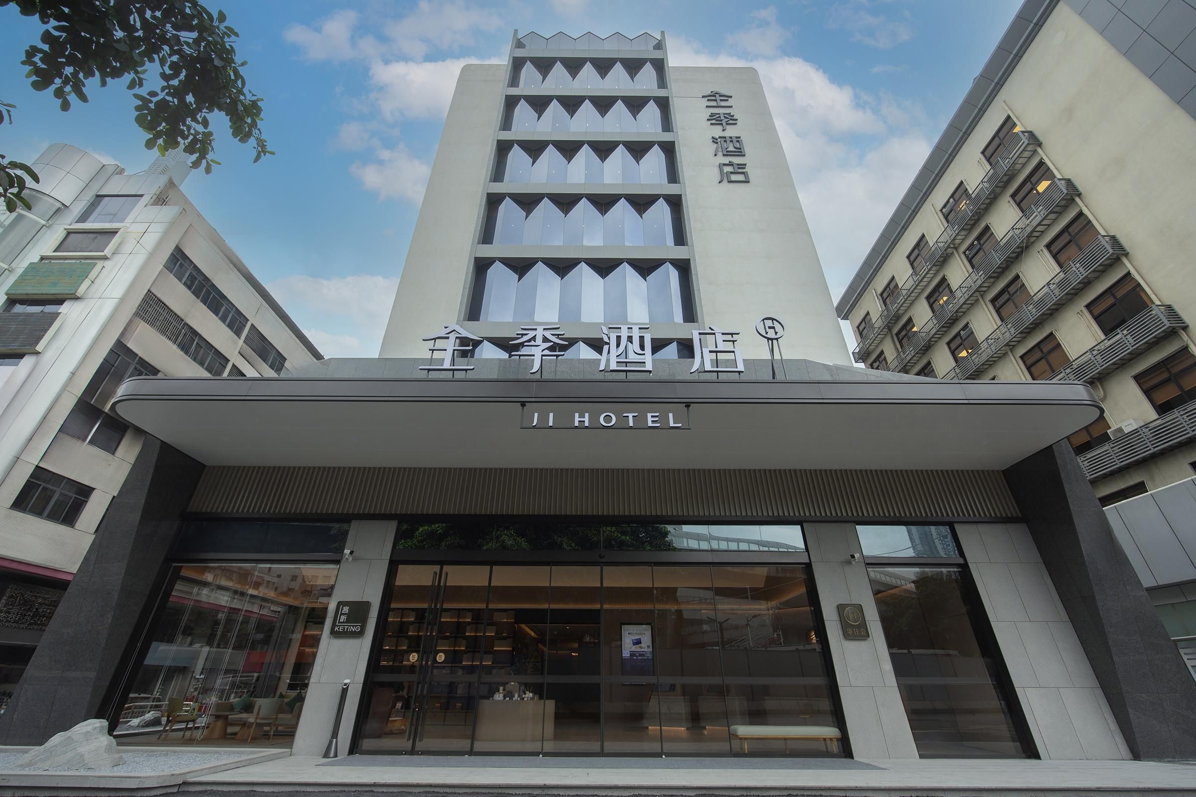 A hotel entrance with a modern design, featuring a prominent sign and a glass facade.