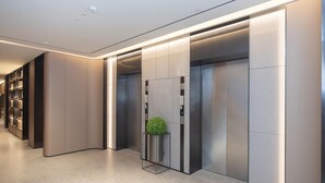 A modern elevator with a green spherical object on the control panel, surrounded by metallic walls and a lighted ceiling. - Ji Hotel Guangzhou Baiyun Station Sanyuanli Avenue (Guangzhou)