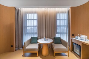 Una habitación de hotel moderna con un conjunto de sofá, una mesa redonda y un minibar.