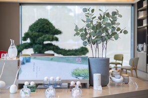 A reception desk with a QR code, a potted plant, and various toiletries.